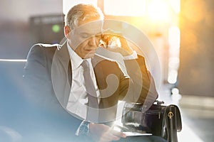 Businessman talking on smartphone while sitting and waiting in his gate for boarding in airport