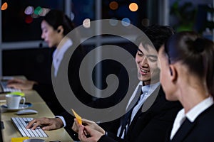 Businessman talking with team and working overtime late at night in call center office