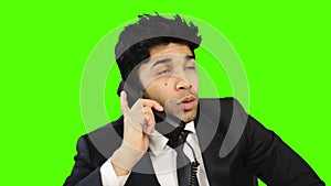 Businessman talking on telephone and showing thumbs up against green background
