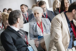 Businessman talking to businesswoman in seminar hall at convention center