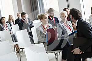 Businessman talking to businesswomen in seminar hall