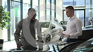 Businessman talking to dealer and choosing new car while standing in retail store spbd.