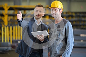 Businessman talking to working man in factory