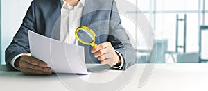 Businessman or tax inspector analyzing document with magnifying glass in office. business financial audit concept. copy space