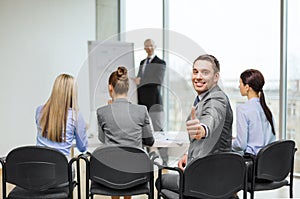 Businessman with team showing thumbs up in office