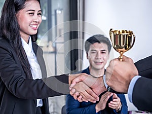 Businessman with teamwork in goal and successful showing trophy and rewarded for in the office photo