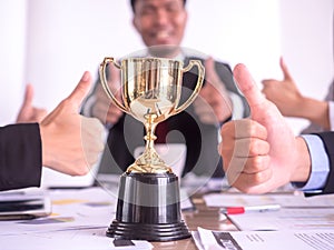 Businessman with teamwork in goal and successful showing trophy and thumb up rewarded for in the office photo