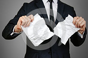 Businessman tearing hands crumpled sheet of A4 paper. o