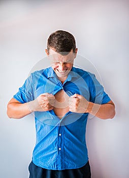 Businessman tearing off his shirt and showing mucular body concept on background