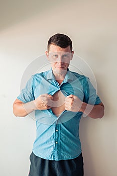 Businessman tearing off his shirt and showing mucular body concept on background