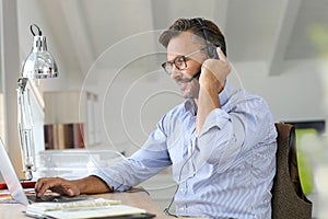 Businessman teleworking with headset on laptop