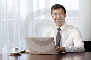 Businessman teleworking at home. On a Laptop. Smiling