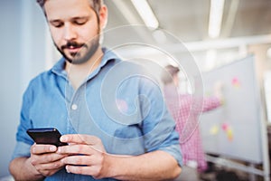 Businessman texting on cellphone at creative office