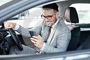 Businessman texting on his mobile phone while driving.