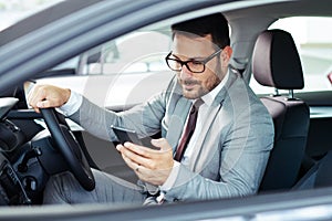 Businessman texting on his mobile phone while driving.