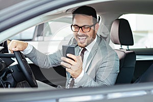 Businessman texting on his mobile phone while driving.