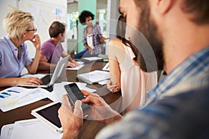 Businessman Texting During Meeting In Office