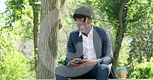 Businessman texting using mobile phone at city park