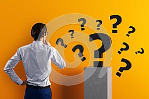 Businessman thinking while looking at floating question marks symbolizing problem solving and curiosity on orange background