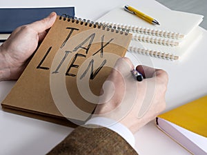 Businessman thinks about tax lien and holds notepad. photo