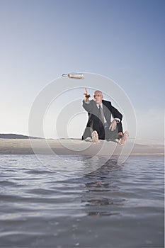 Businessman Throwing Bottle With Message Into Sea