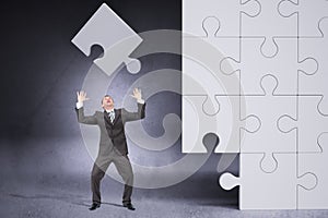 Businessman throwing on grey puzzle piece