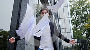 Businessman throwing papers documents into air and celebrates success on office building background. Freedom, successful
