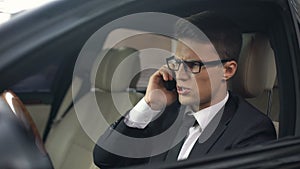 Businessman throwing phone out car window after telephone call, bad news