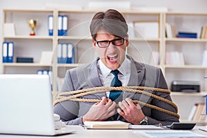 The businessman tied up with rope in office