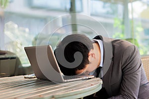 Businessman tiring and sleeping on his laptop in outdoor scene photo