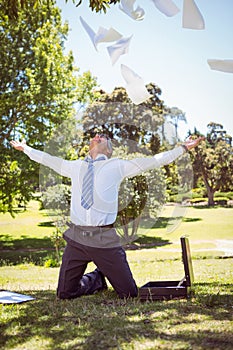 Businessman tossing papers in the park