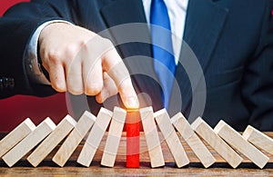 Businessman with a touch stops process of falling dominoes. Risk management concept. Successful strong business, problem solving.