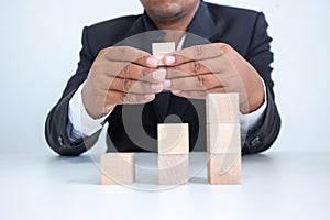 Businessman touches the woodblocks placed on the  table