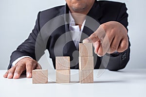 Businessman touches the woodblocks placed on the  table