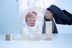 Businessman touches the woodblocks placed on the  table