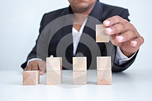 Businessman touches the woodblocks placed on the  table