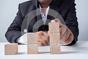 Businessman touches the woodblocks placed on the  table