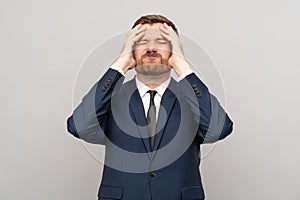 Businessman touching head with frown disappointed sickly emotional face isolated studio background.