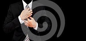 Businessman touching necktie, isolated on black background with copy space