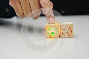 Businessman touching a wooden block cube with satisfaction icon symbol. Emotion and mindset concept.