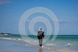 Businessman tourist in casual suit barefoot walking on tropical beach with laptop. Handsome business man on summer