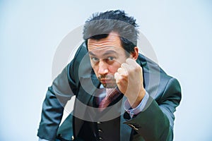 businessman with tousled hair looks at the camera shaking his fist