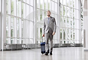 Businessman with travel bag walking along office