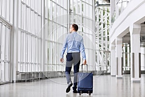 Businessman with travel bag walking along office