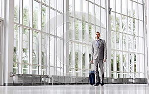 Businessman with travel bag walking along office