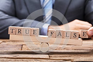 Businessman With True And False Wooden Blocks On Seesaw photo