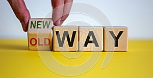 Businessman turns a cube and changes words `old way` to `new way`. Beautiful yellow table, white background. Copy space. Conce