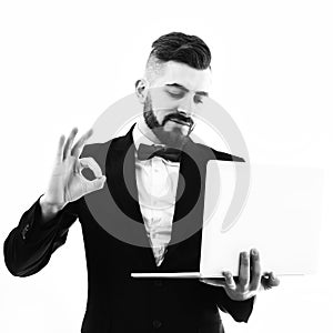 Businessman or TV announcer shows OK sign and holds laptop