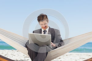 Businessman typing on his laptop in a hammock