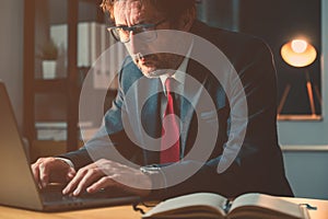 Businessman typing laptop computer keyboard in the office late at night